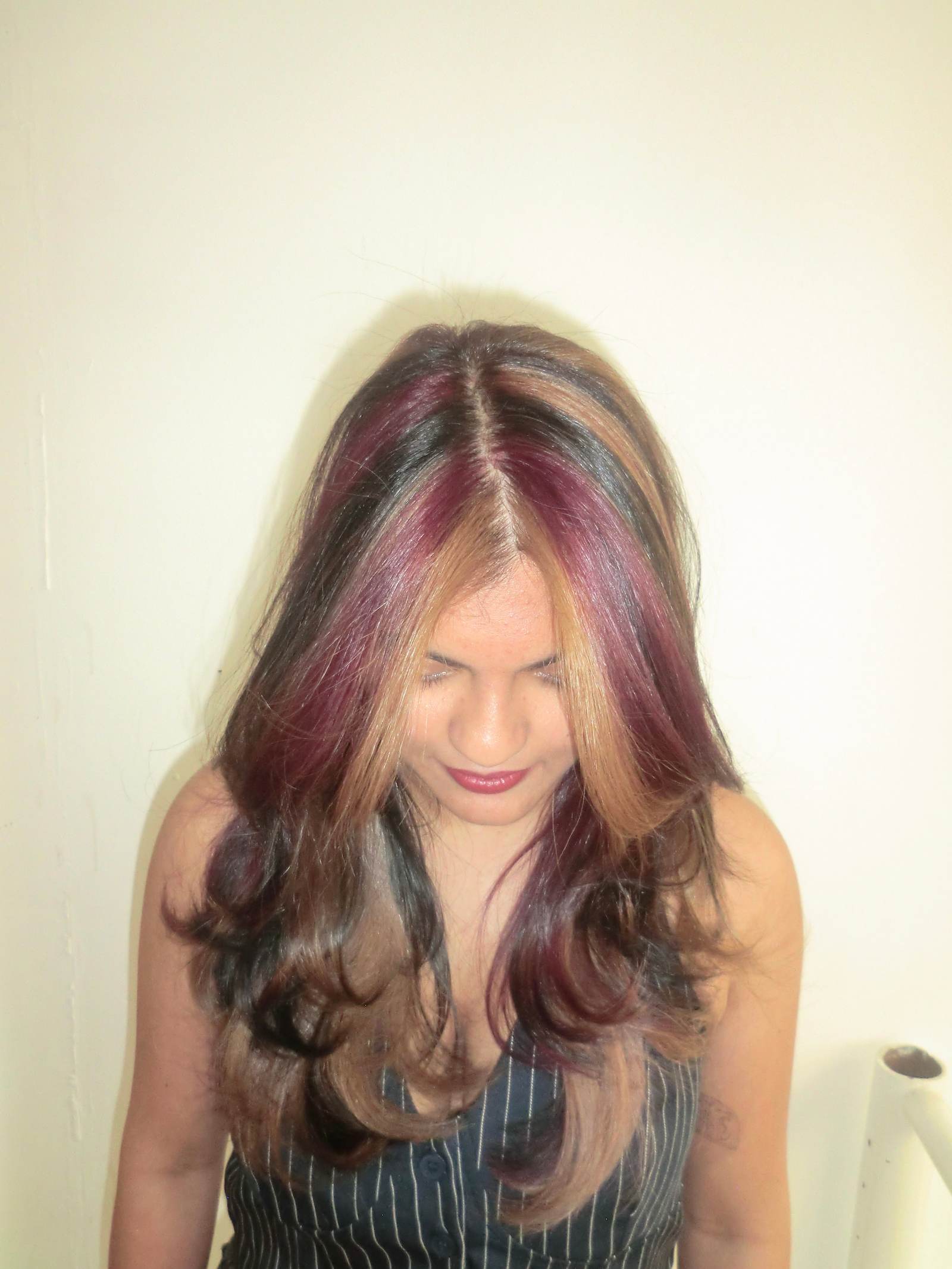 A front profile portrait of a modern "natural calico" hairstyle. The natural black hair base features finely woven, smaller sections of deep mahogany red and warm, bronzy-blonde highlights. This dimensional blend creates a soft, dappled, and high-contrast look that frames the face with rich color without large, blocky sections.