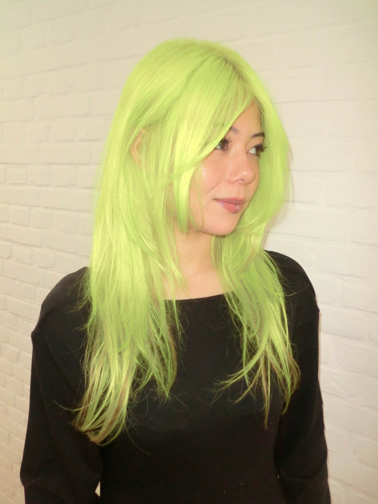 A vibrant after-shot of the complete hair transformation. The roots and lengths have been flawlessly lifted and saturated in a high-visibility, electric neon yellow shade. The color is completely uniform from the scalp to the tips, giving off a bold, glowing, and monochromatic look.