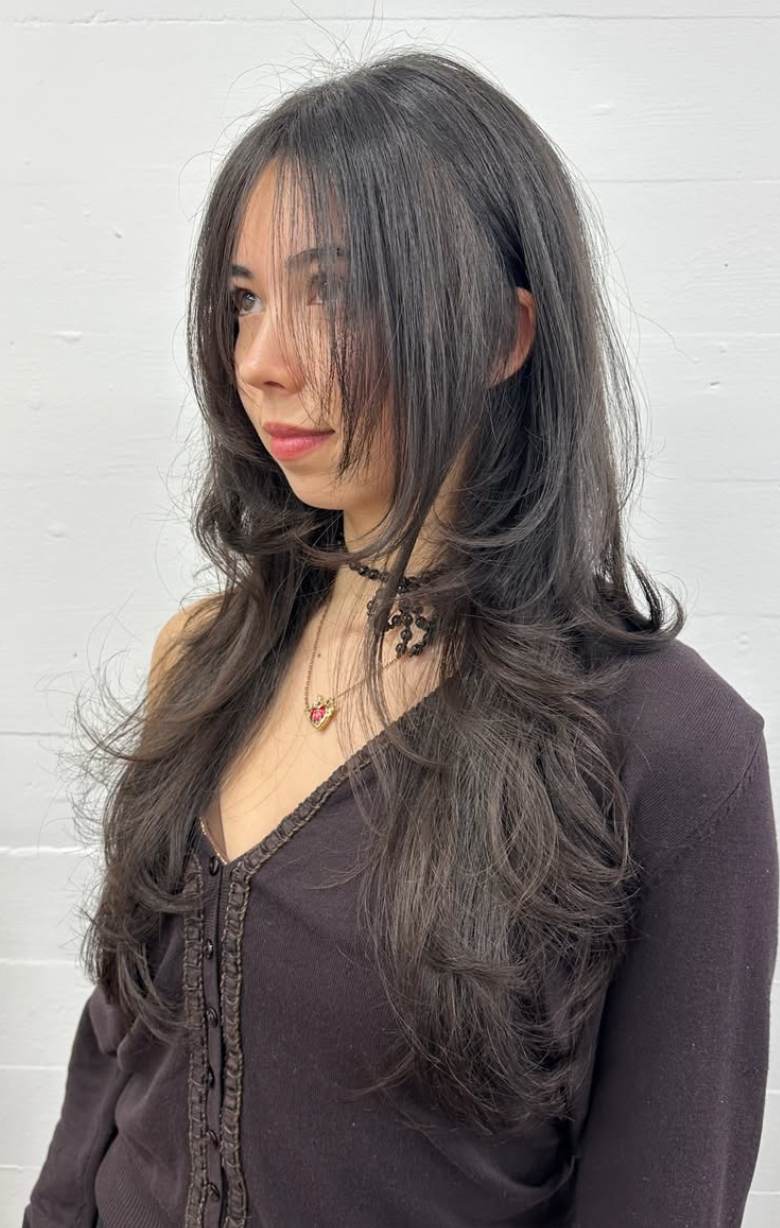 A close-up showcasing hair styled with distinct, feathered layers that create volume and movement. The ends are flicked outward to emphasize the tiered texture and flow of the cut.