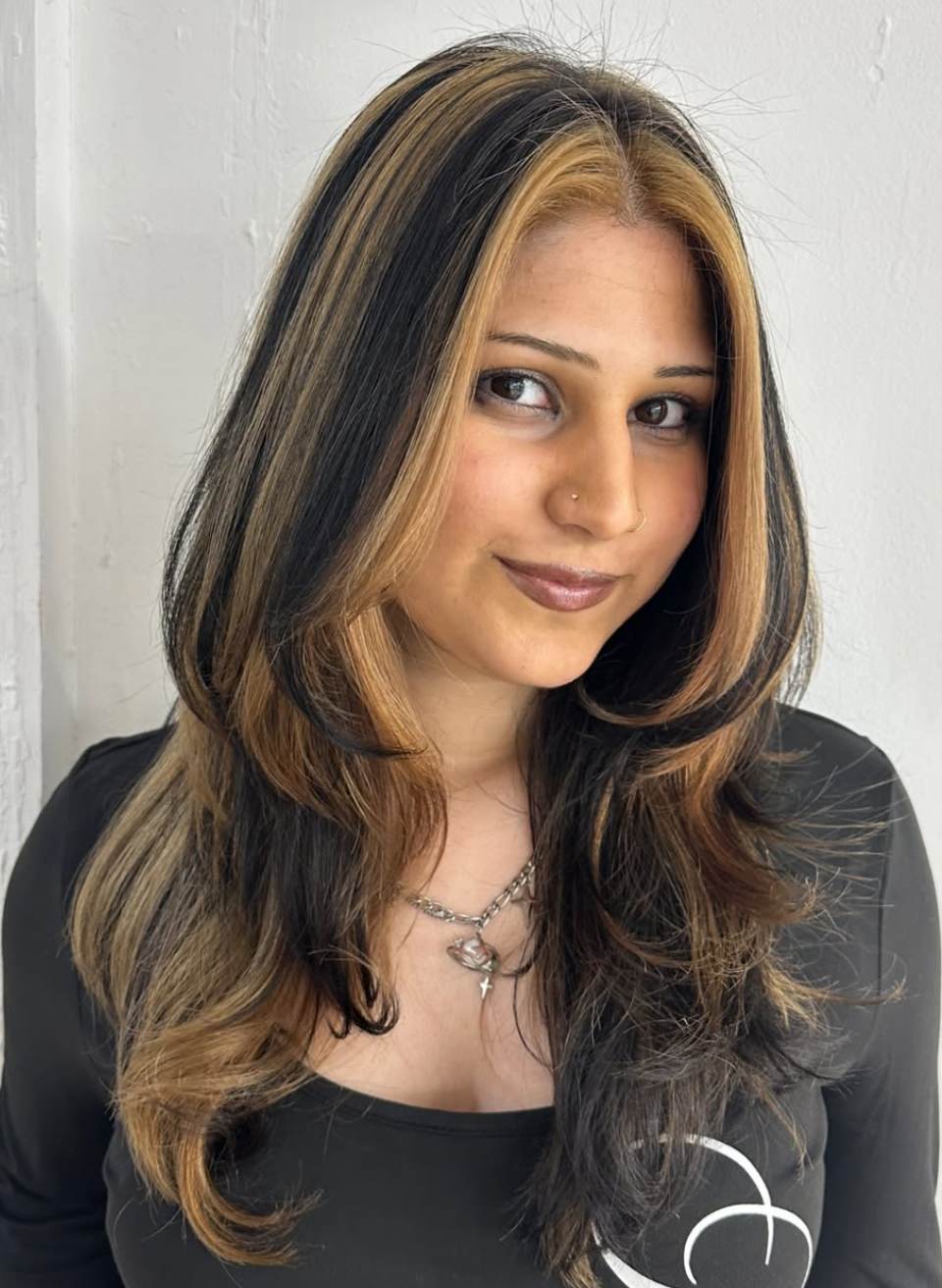 A close-up showcasing hair styled with distinct, feathered layers that create volume and movement. The ends are flicked outward to emphasize the tiered texture and flow of the cut.