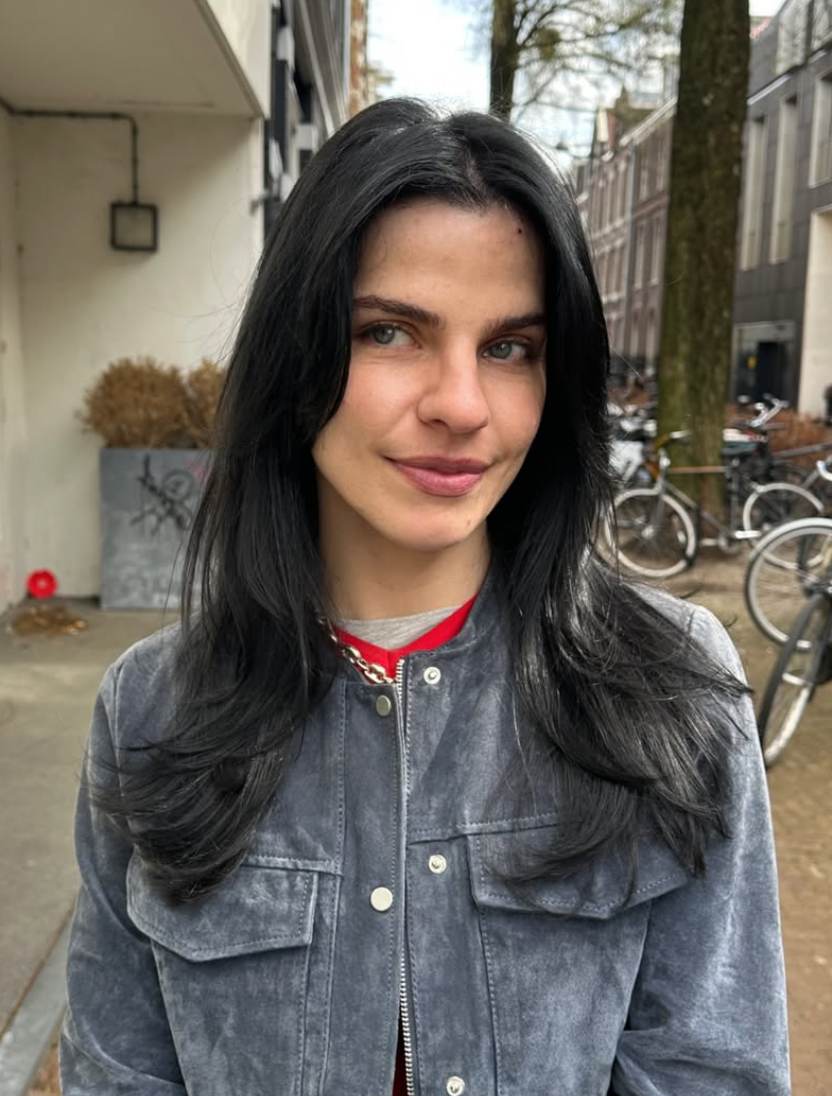 A close-up showcasing hair styled with distinct, feathered layers that create volume and movement. The ends are flicked outward to emphasize the tiered texture and flow of the cut.