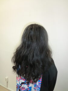 A back view of a person with long, dark brunette hair that has a natural, slightly wavy texture.