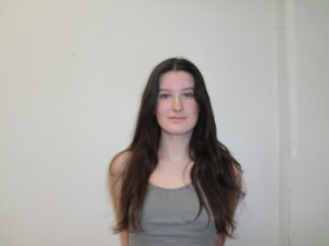 A frontal portrait of a person with long, dark espresso-colored hair parted in the middle. The hair has a natural, soft wave and reaches down past the shoulders.