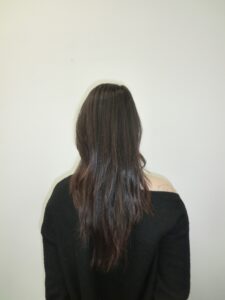 A back view of a person showing their long, dark hair falling past the shoulders in a natural V-shape
