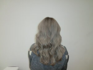 A back view of the same long hair, now transformed into an even, muted "milk tea" or "sesame gray" shade. The color is a sophisticated blend of cool-toned ash and soft charcoal, creating a smoky, translucent finish from roots to ends. The hair is styled with a sleek, straight texture that highlights the multi-dimensional gray tones.