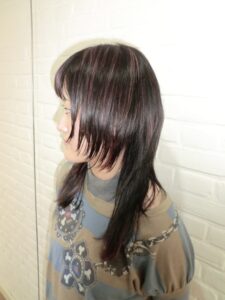 A side profile of long black hair featuring high-contrast pink highlights. The pink color is applied in vertical sections, blending with the natural black base to create a bold, streaked appearance from the crown to the ends.