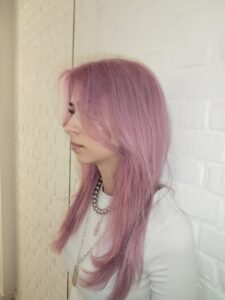 A side profile view of hair that has been colored entirely in a bright, uniform pink shade. The hair is styled straight, showcasing the consistent saturation of the pink color from the roots down to the ends.