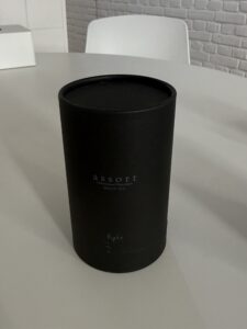 A detailed view of the Assort Multi Oil Light packaging. It is housed in a tall, matte black cylinder bottle with a sleek dropper top and a crisp white label. It stands at the same height as the "Rich" oil, completing the uniform and sophisticated Assort product lineup.