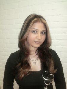 A front profile portrait of a person with "skunk highlights." The style features high-contrast, chunky platinum blonde streaks framing the face, contrasted against a deep jet-black base. The two-tone sections are thick and bold, creating a graphic, symmetrical look around the forehead and eyes.