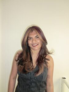 A front profile portrait of a modern "natural calico" hairstyle. The natural black hair base features finely woven, smaller sections of deep mahogany red and warm, bronzy-blonde highlights. This dimensional blend creates a soft, dappled, and high-contrast look that frames the face with rich color without large, blocky sections.