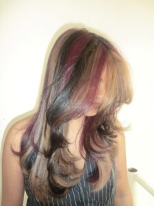 A side profile view showcasing the intricate color blending of the natural calico style. The natural dark black hair is intricately interwoven with small, delicate strands of dark red and bronzy-copper blonde. The finely sectioned highlights follow the natural movement of the waves, demonstrating a sophisticated, multi-tonal, and earthy patchwork effect from the ear to the shoulder.