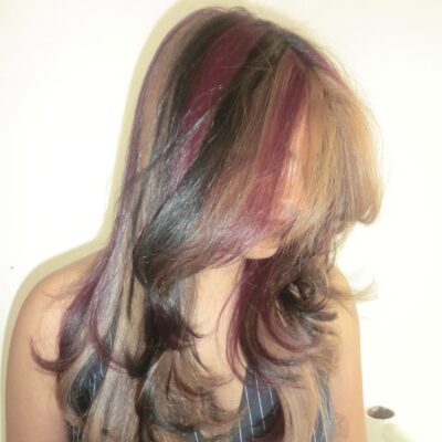 A side profile view showcasing the intricate color blending of the natural calico style. The natural dark black hair is intricately interwoven with small, delicate strands of dark red and bronzy-copper blonde. The finely sectioned highlights follow the natural movement of the waves, demonstrating a sophisticated, multi-tonal, and earthy patchwork effect from the ear to the shoulder.