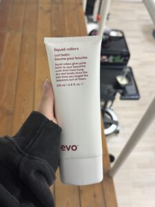 A 200ml squeeze tube of Evo "Liquid Rollers" curl balm. The tube is white with minimalist black lettering. It is a styling balm used to enhance curls, reduce frizz, and provide a soft, touchable hold.