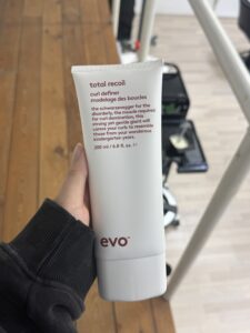 A 200ml squeeze tube of Evo "Total Recoil" curl definer. The packaging is a clean, matte white tube with simple black branding. This product is a strong-hold cream used for defining and shaping curls.