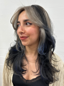 A front profile of a multi-colored "calico" hairstyle. The look features chunky sections of platinum blonde that ombre into a deep ocean blue at the ends, contrasted against solid black sections. The hair is styled to show the sharp color blocks framing the face.
