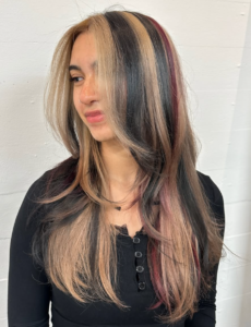 A front profile featuring a striking calico blend of jet black, bright blonde, and dark red. The colors are placed in distinct, chunky sections that frame the face and forehead for a bold, graphic appearance.