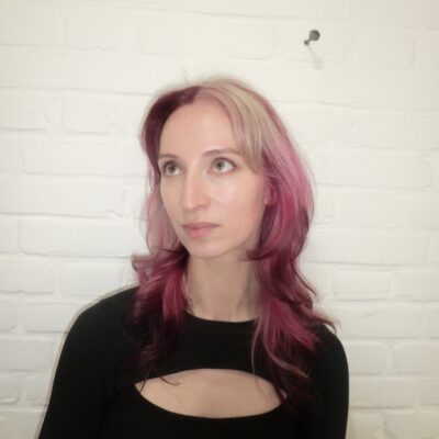 A back view of a high-impact colorblocking hair design. The hair is divided into distinct, bold sections of metallic silver, vibrant hot pink, and deep crimson red. The colors are applied in large, clean blocks that contrast sharply against one another, creating a modern, graphic art effect across the straight lengths.