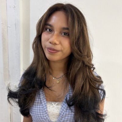 A view of the hair transformed into a rich chestnut brown shade. The warm, reddish-brown color is uniform throughout the main lengths, contrasting sharply with the very ends, which are dipped in a solid jet-black pigment to create a clean, graphic tip-dyed effect.