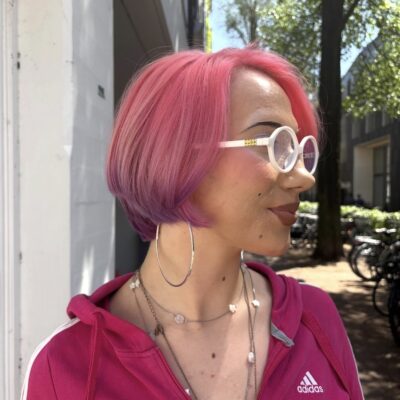 A front profile view of a sharp, chin-length bob haircut. The primary color is a vibrant, neon hot pink that transitions cleanly along the bottom perimeter into a contrasting rich purple dip-dye at the blunt ends.