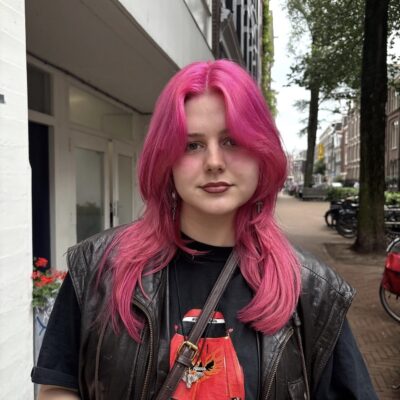 A front profile view of hair completely saturated in a fresh, bright, and vibrant hot pink color. The rich pink hue evenly coats the hair from the roots all the way down the face-framing lengths, creating a high-impact, uniform look.