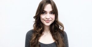A front profile of a person with long, waist-length wavy hair. The color is a dimensional blend of medium brown and sandy blonde highlights. The hair is styled in voluminous, beachy waves that frame the face and cascade down the shoulders.