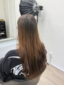 A back view of shoulder-length hair in a solid, uniform medium brown shade. The hair has a natural, healthy texture and is styled straight with a clean, blunt hemline, serving as the starting "before" state.