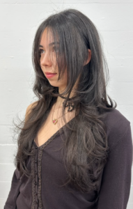 A close-up showcasing hair styled with distinct, feathered layers that create volume and movement. The ends are flicked outward to emphasize the tiered texture and flow of the cut.