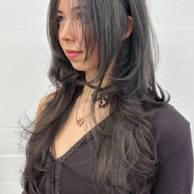 A close-up showcasing hair styled with distinct, feathered layers that create volume and movement. The ends are flicked outward to emphasize the tiered texture and flow of the cut.